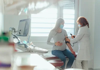 A pregnant woman gets her blood pressure checked by a doctor A pregnant woman gets her blood pressure checked by a doctor